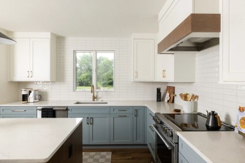 Taylors U-shaped kitchen with two-tone cabinetry, white upper cabinets, light blue-grey lower cabinets, white quartz countertops, subway tile backsplash, and custom range hood by Tekton Builds.